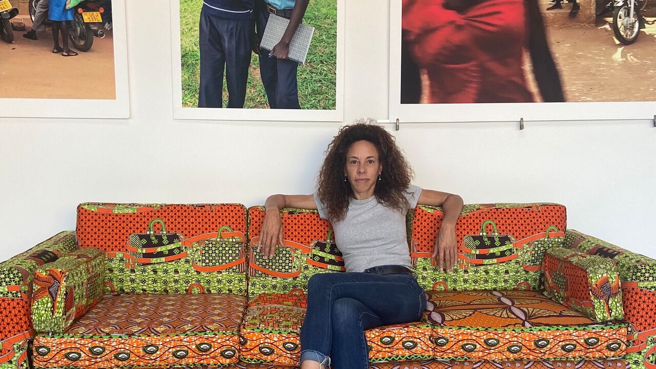 2025 Artist Fellowship grantee Nicola Goode sits on a couch below her photos hanging on the wall