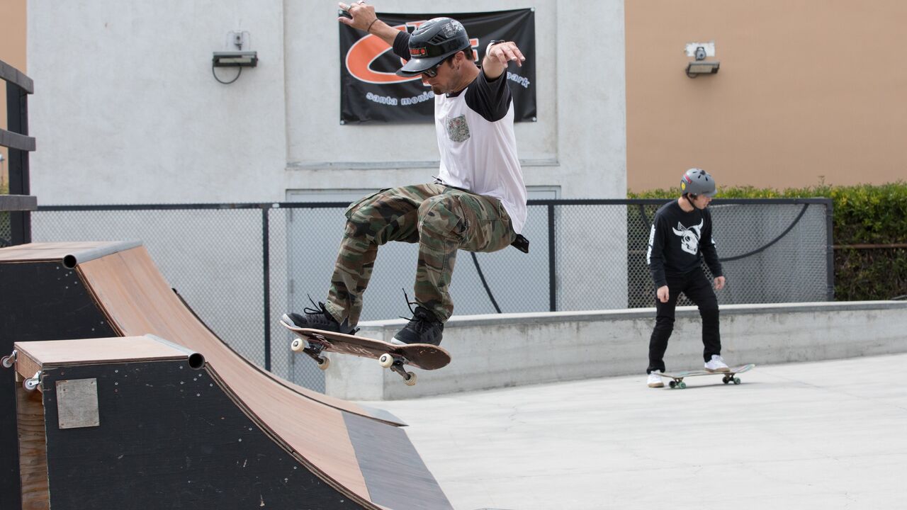 Skateboarder launching of ramp at The Cove skatepark with another skateboarder in the background